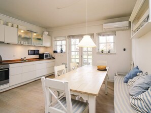 Une cuisine moderne avec des meubles blancs, un plan de travail en bois et un coin repas comprenant une table et des chaises en bois.