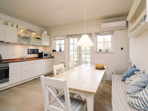 Eine moderne Küche mit weißen Schränken, einer Holzauskładung und einem Essbereich mit einem Holztisch und Stühlen.
