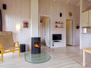 Une pièce avec un poêle à bois, une télévision et une chaise en bois.