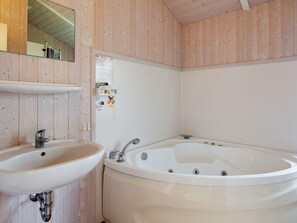 Un baño con lavamanos, bañera y paredes de madera.