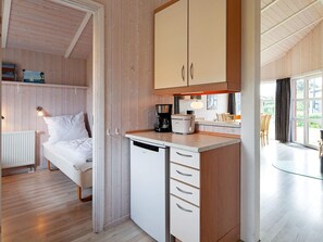 Una habitación pequeña con cama, kitchenette y vistas por la ventana.