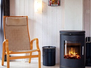A room with a wooden chair, a black heater, and a small black trash can.
