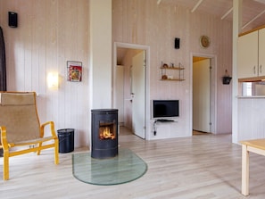 A cozy living room with a central wood-burning stove, a television, and a wooden chair.