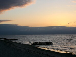 A beach with a wooden pier extending into the water during sunset. - Holiday Home in GrÃ¶mmitz (Groemitz)