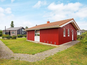 A red single-story house with a tiled roof, a front door, and a small porch area.