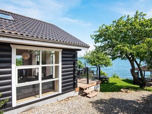 Eine Blockhütte mit einem großen Fenster, einer Terrasse und Seeblick.