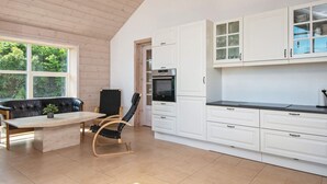 A modern kitchen with white cabinetry, a black countertop, and a dining area with a table and chairs. - Panoramic Retreat by Water (Borkop)