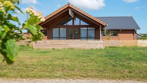 Ein modernes Holzhaus mit einer großen Veranda, großen Fenstern und einem geneigten Dach.