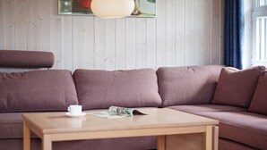 Een moderne woonkamer met een houten salontafel, een bruine bank en een schilderij aan de muur.