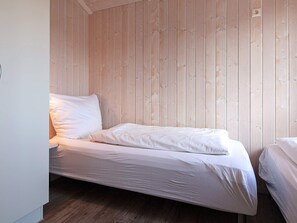 A single bed with white bedding in a room with wooden panel walls and a wooden floor. - Holiday Home in GrÃ¶mmitz (Groemitz)