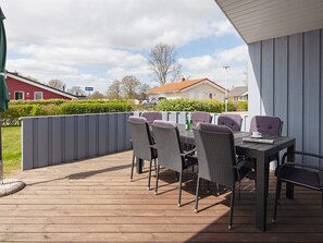 An outdoor patio with a wooden deck, wicker chairs, and a table. - Holiday Home in GrÃ¶mmitz (Groemitz)