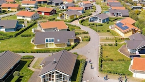 A residential area with houses, a central road, and a large building with a glass facade. - Holiday Home in GrÃ¶mmitz (Groemitz)