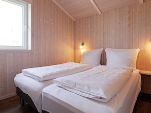 Uma cama de casal em quarto com paredes de madeira e janela.