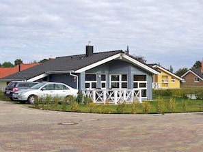 A residential area with houses, a paved driveway, and a white car parked in front. - Holiday Home in GrÃ¶mmitz (Groemitz)
