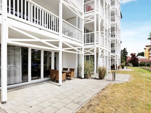 A multi-story building with balconies, large windows, and outdoor seating. - Holiday Home in Grossenbrode (Grossenbrode)