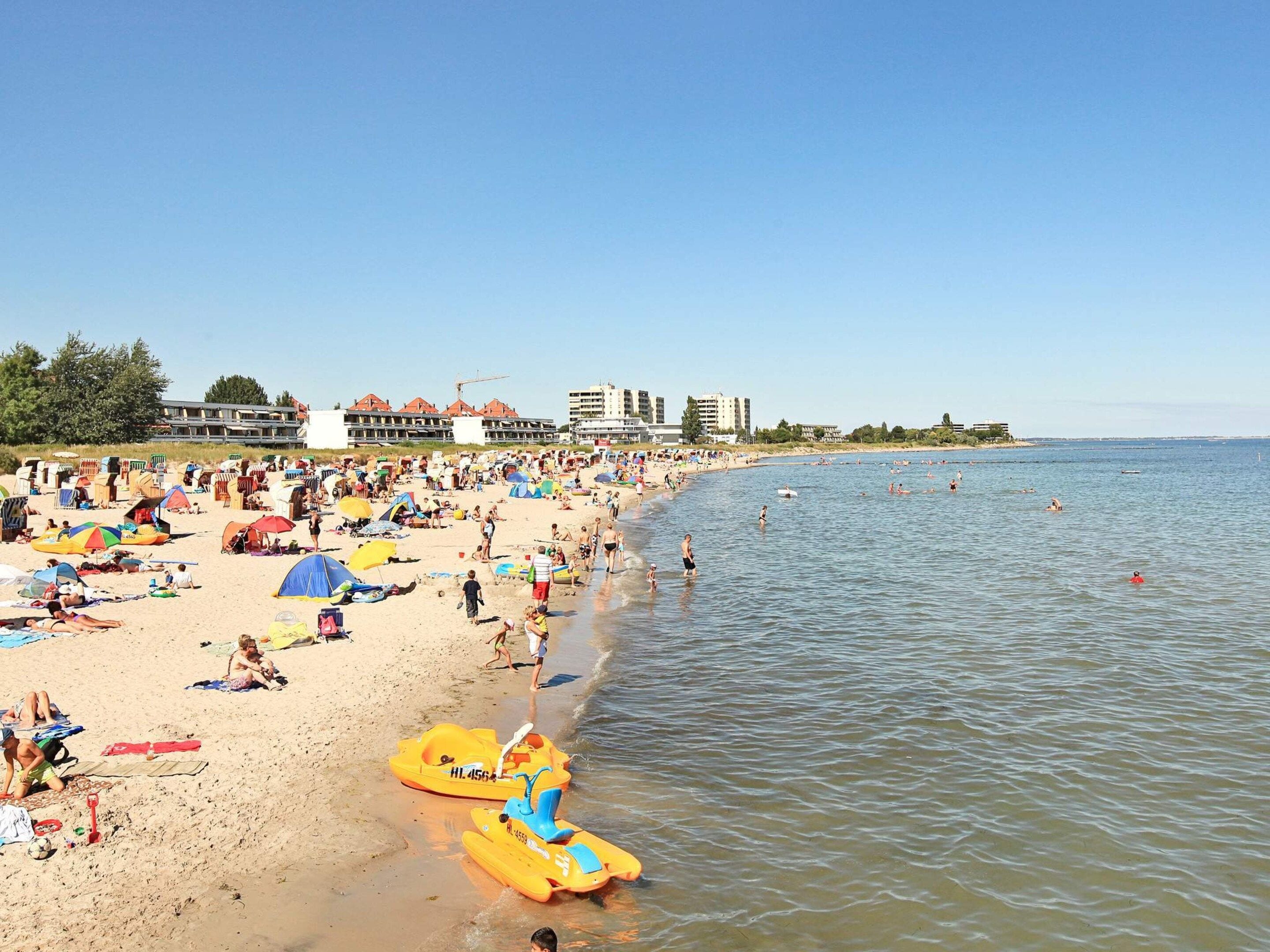 Una playa con múltiples sombrillas y gente disfrutando del agua.