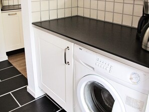A front view of a washing machine with a control panel, a door handle, and a black countertop above it. - Cozy Holiday Home in Sæby near Sea (Sæby)
