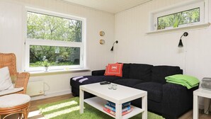 Ett mysigt vardagsrum med en svart soffa, ett vitt soffbord och en grön matta.