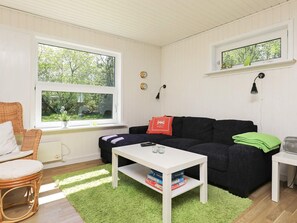 A cozy living room with a black sofa, a white coffee table, and a green rug. - Cozy Holiday Home in Sæby near Sea (Sæby)