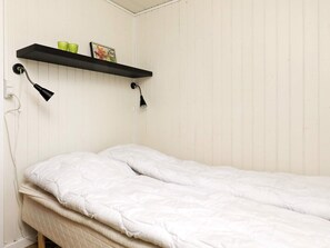 A single bed with white bedding in a room with white walls and a black shelf above. - Cozy Holiday Home in SÃ¦by near Sea (Sæby)