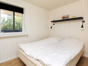 A bedroom with a bed, a window, and a shelf with items. - Cozy Holiday Home in SÃ¦by near Sea (Sæby)