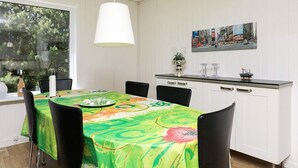 En matplats med ett bord dukat för fyra personer, en hängande lampa och en målning av en stadsbild på väggen.
