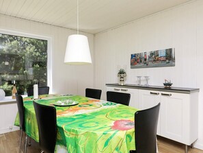 A dining area with a table set for four, a hanging light fixture, and a cityscape painting on the wall. - Cozy Holiday Home in Sæby near Sea (Sæby)