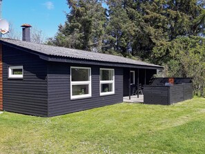 A single-story building with a dark exterior, a small window, and a door. - Cozy Holiday Home in SÃ¦by near Sea (Sæby)
