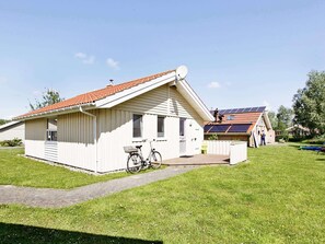 A single-story white building with a sloped roof, a satellite dish, and a bicycle parked in front.