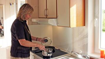 A person cooking on a stove in a kitchen with wooden cabinets and a window.