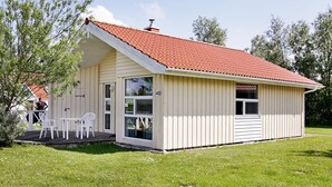 En lille, etetages bygning med røde tegltagsten, en overdækket veranda med hvide stole og et skilt med nummer 48.
