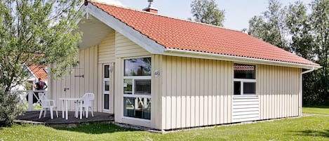 A small, single-story building with a red-tiled roof, a covered porch with white chairs, and a number '48' sign.