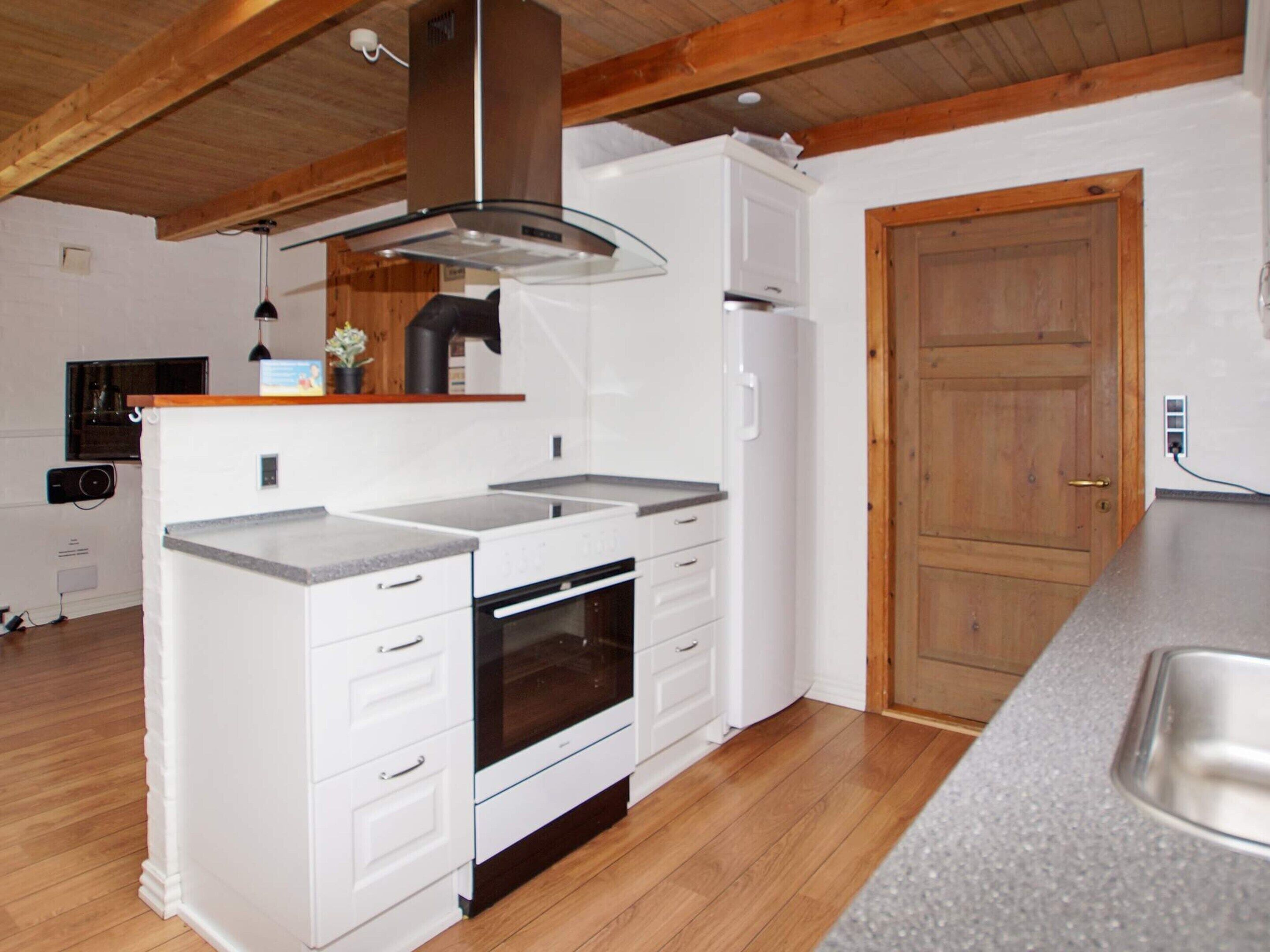 A compact kitchen with white cabinetry, a built-in oven, and a wooden ceiling.