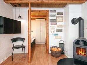A cozy room with a wooden floor, a black chair, a TV, a fireplace, and motivational wall art. - 4 Star Holiday Home in Hemmet (Hemmet)