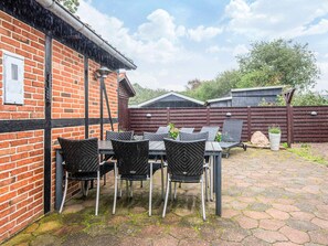 A patio with a brick wall, a table with chairs, and a wooden fence in the background. - 4 Star Holiday Home in Hemmet (Hemmet)