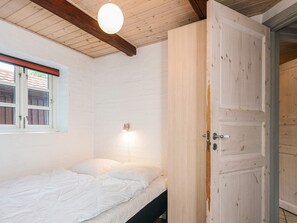 A bedroom with a single bed, a window with curtains, a wall-mounted light, and a wooden door. - 4 Star Holiday Home in Hemmet (Hemmet)