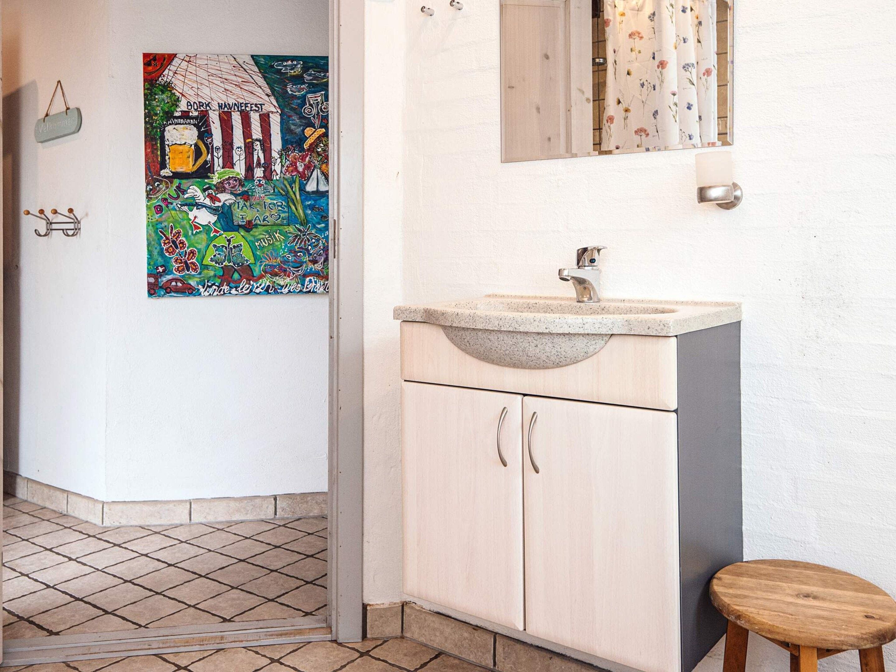 A bathroom with a sink, mirror, and a colorful artwork on the wall.