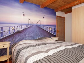 Un dormitorio con cama, mesita de noche, una silla y una puerta.