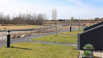 Un espace extérieur aménagé avec un chemin de gravier, de la pelouse et un petit élément décoratif aquatique.
