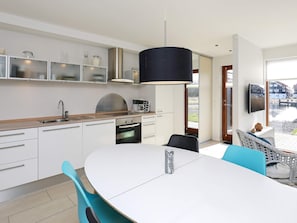 Una cocina moderna con horno integrado, una mesa de comedor con sillas y un amplio ventanal con vistas al agua.