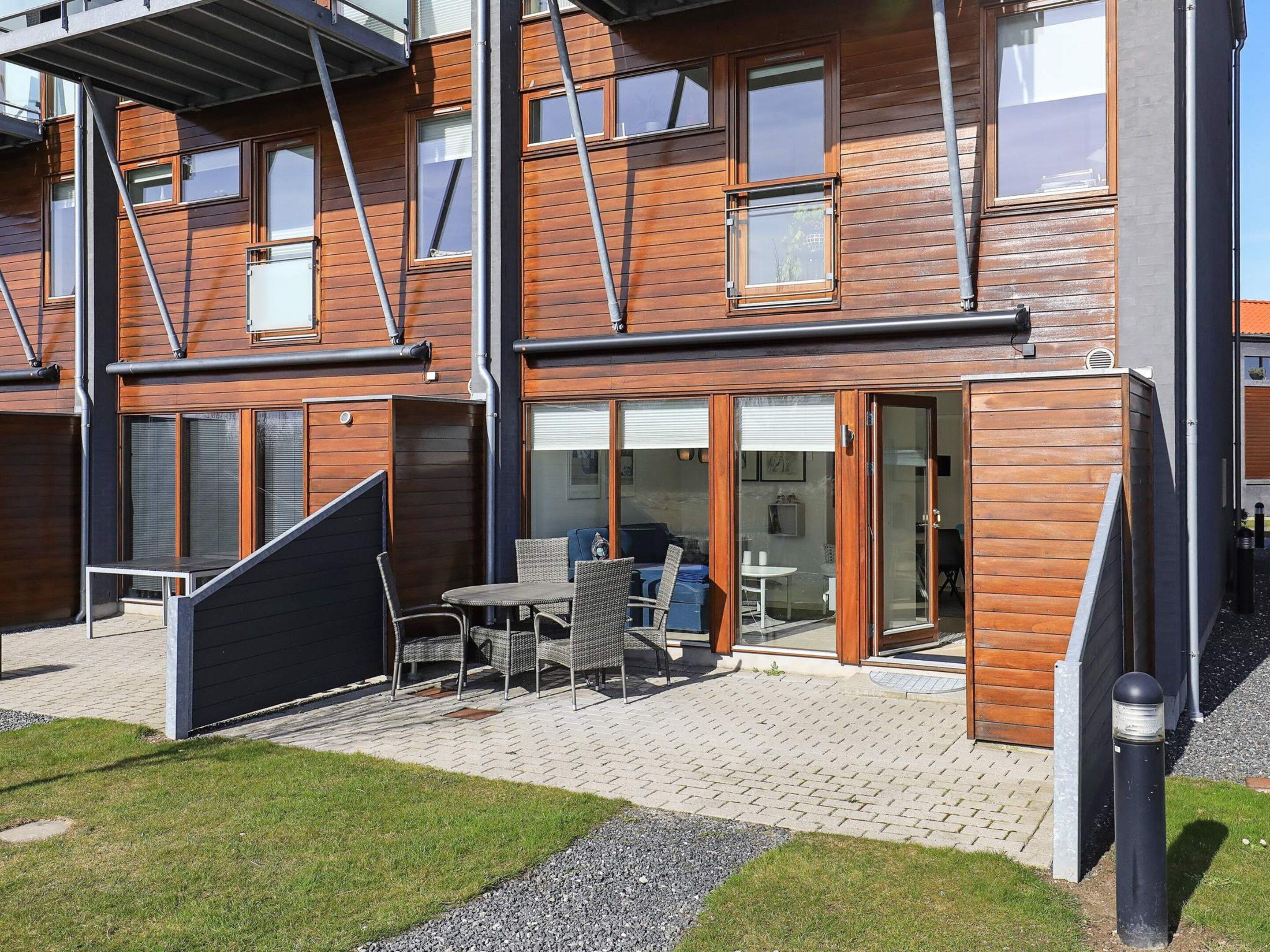 Ein modernes, mehrstöckiges Gebäude mit einer Terrasse, Sitzmöbeln und einem überdachten Sitzbereich.