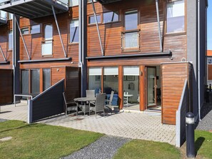 Un edificio moderno de varios pisos con un patio amoblado y una zona de estar techada.