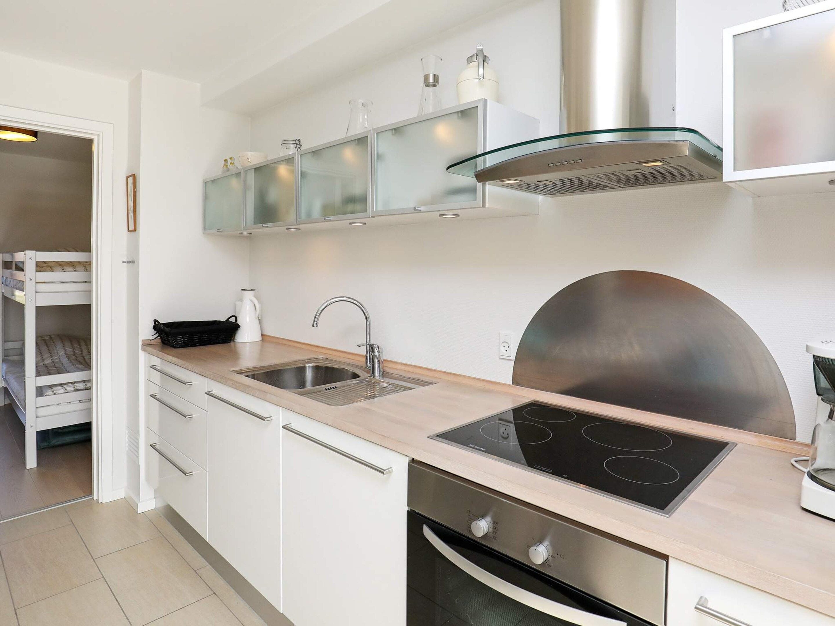 Eine moderne Küche mit Backofen, Edelstahl-Dunstabzugshaube und einem Küchenschrank mit Glasfront.