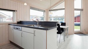 Una cocina moderna con una isla central, un fregadero y una zona de comedor con mesa y sillas.