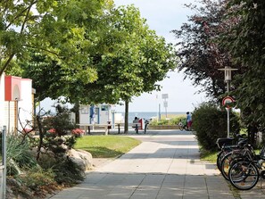 A pathway leading to a beach area with a lifeguard tower, a bicycle, and a sign indicating a no bicycle zone. - Holiday Home in Großenbrode (Grossenbrode)