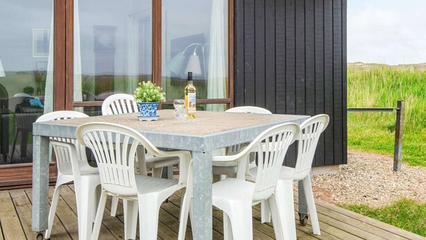 Een eethoek met een tafel, stoelen, een fles wijn en een potplant.