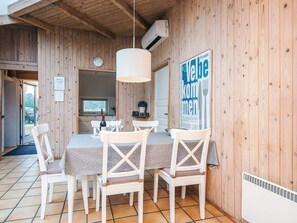 A wooden interior with a dining area featuring a table and chairs, a kitchen visible through an open door, and a sign on the wall. - Beautiful Holiday Home in Vejers Strand with Hot Tub (Vejers Strand)
