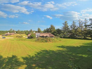 A rural setting with a thatched-roof building, a grassy field, and trees. - Beautiful Holiday Home in Vejers Strand with Hot Tub (Vejers Strand)