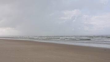 A beach with a wide sandy shore and waves approaching the beach.