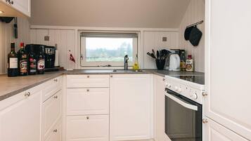 A kitchen with white cabinets, a window, a stove, and various kitchen items on the counter.